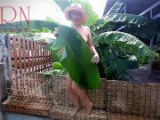 Rural striptease. Country girl dancing in the yard of her house Rustic striptease with banana leaf 2/16